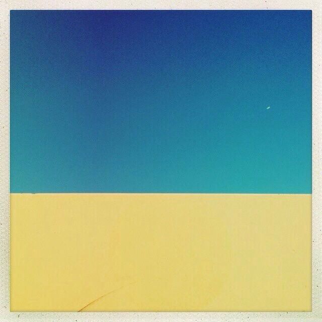 Low angle view of yellow wall against clear blue sky