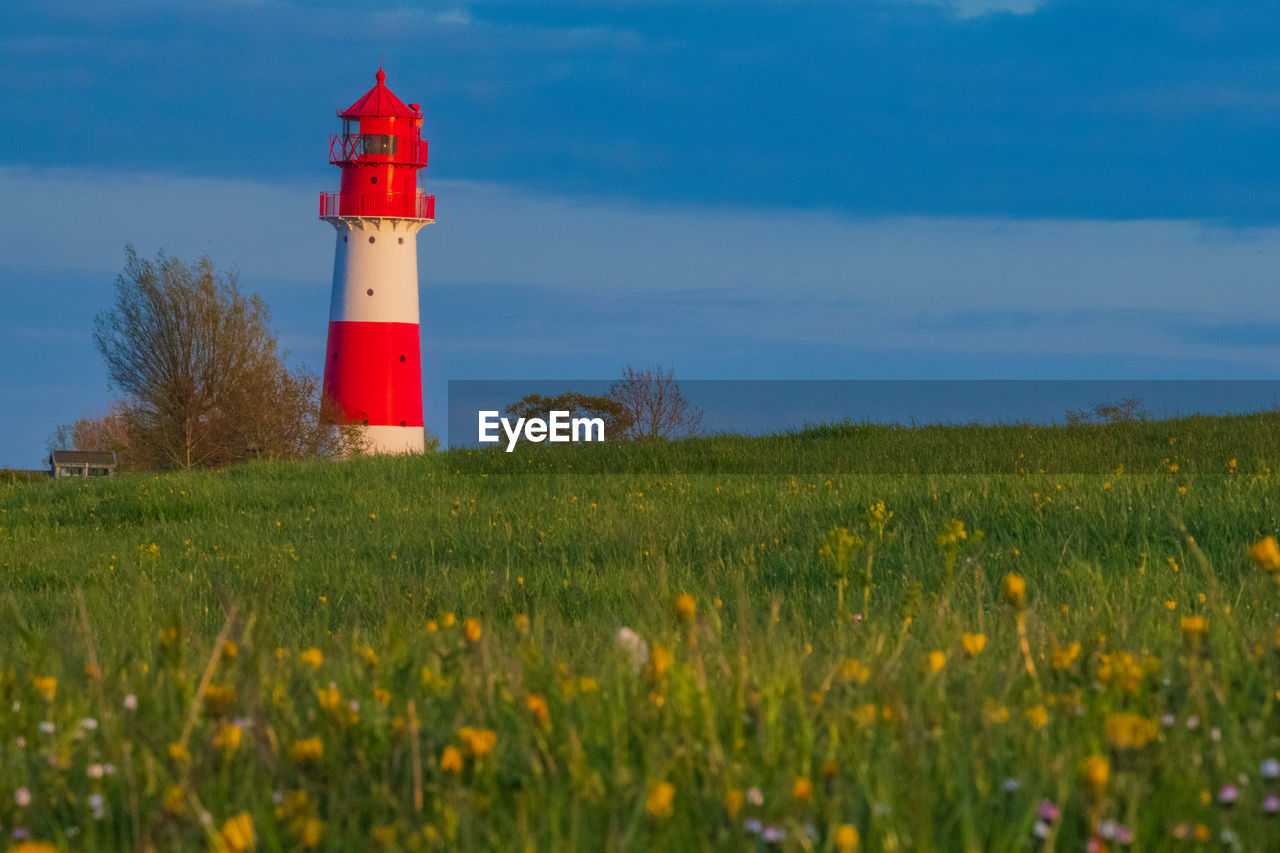 LIGHTHOUSE AMIDST FIELD AGAINST SKY