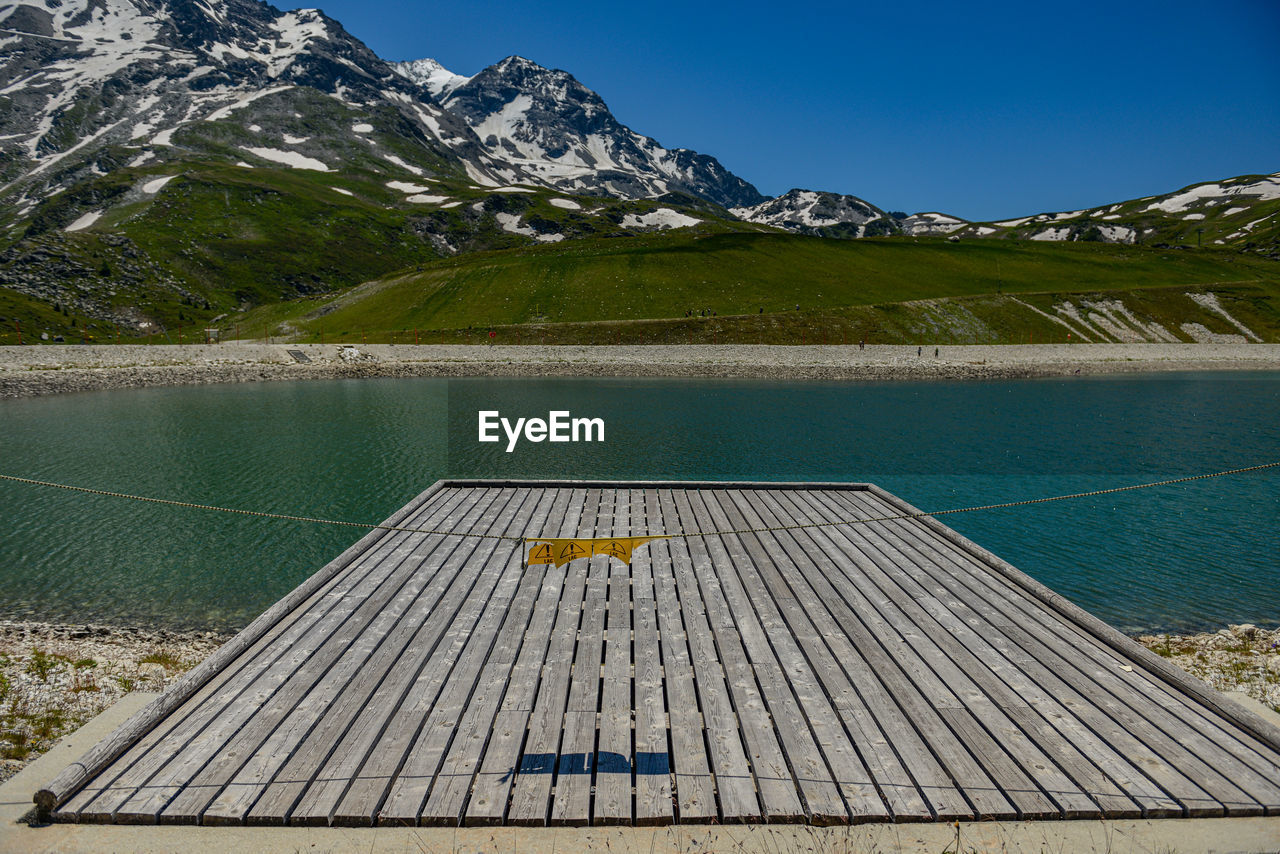 View of wooden ramp by lake against mountain