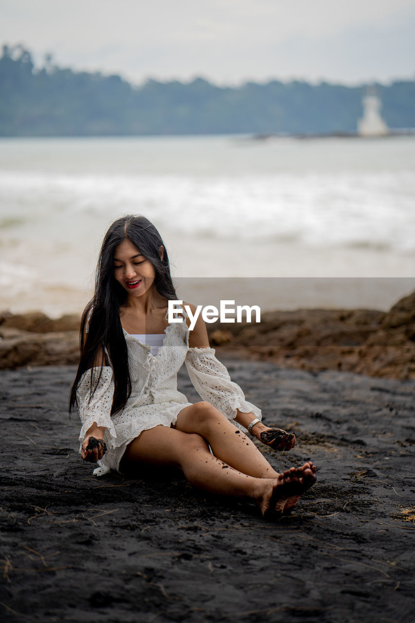 BEAUTIFUL WOMAN SITTING ON BEACH