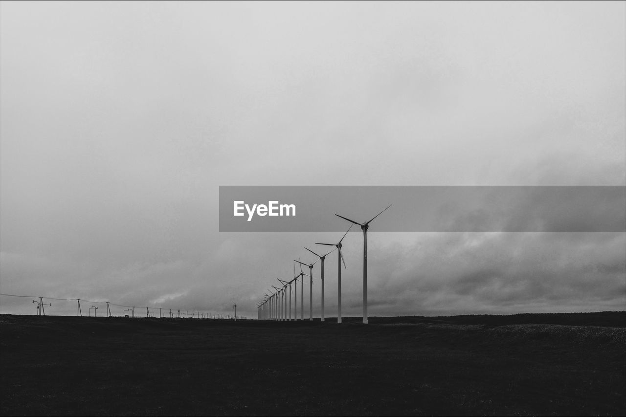 Windmills on field against sky