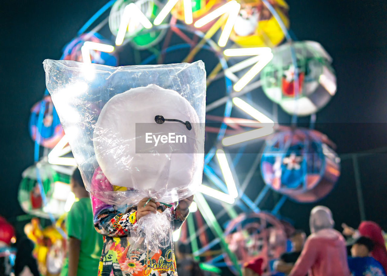 Low angle view of man holding cotton candy at amusement park