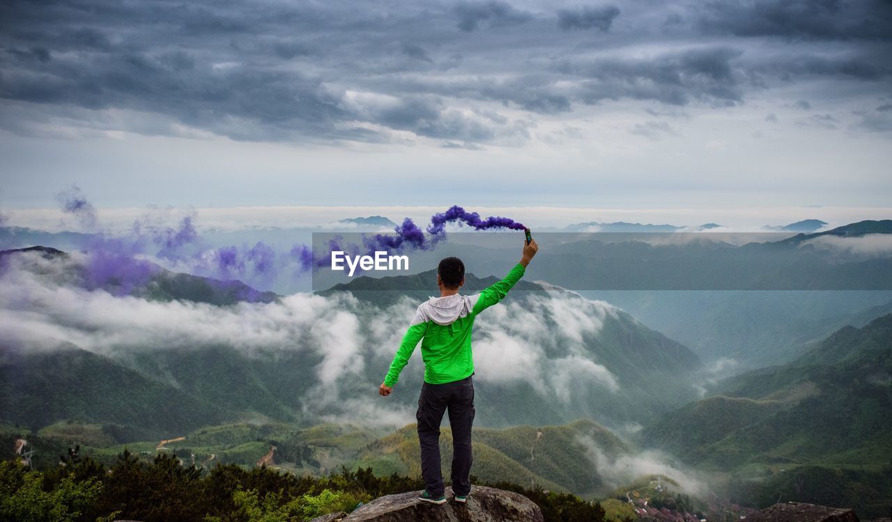 FULL LENGTH OF MAN STANDING AGAINST MOUNTAINS