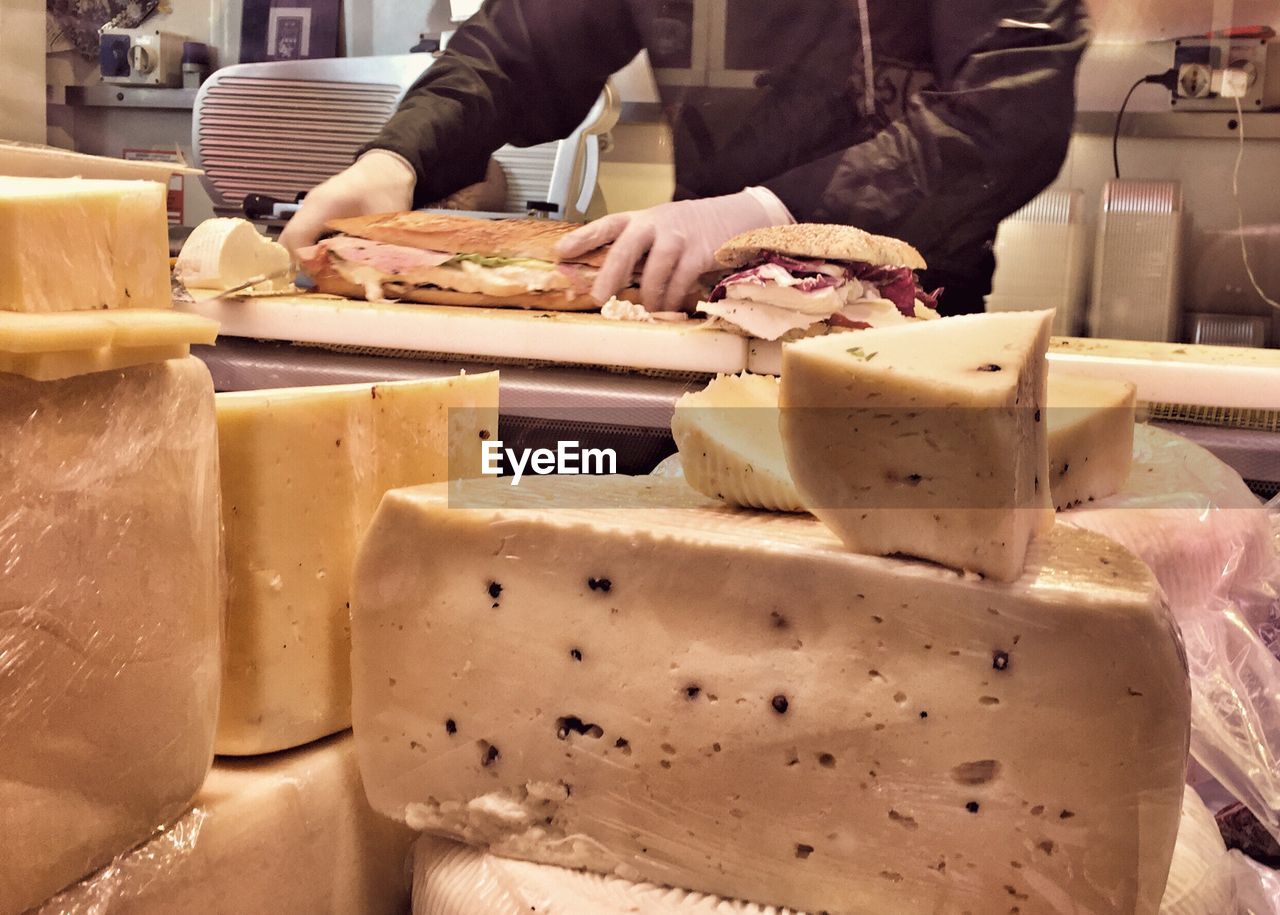 Close-up of cheese with man preparing sandwich
