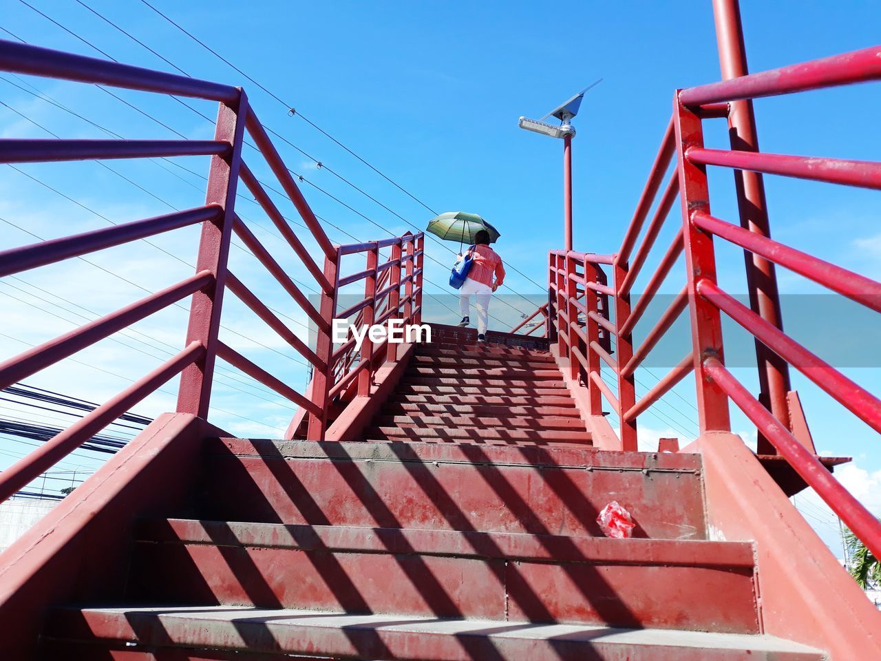 LOW ANGLE VIEW OF RED STEPS BY BUILDING AGAINST SKY