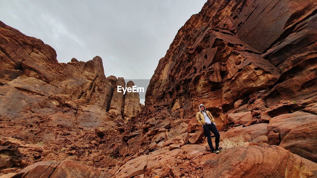 Low angle view of man standing on rock formation against sky