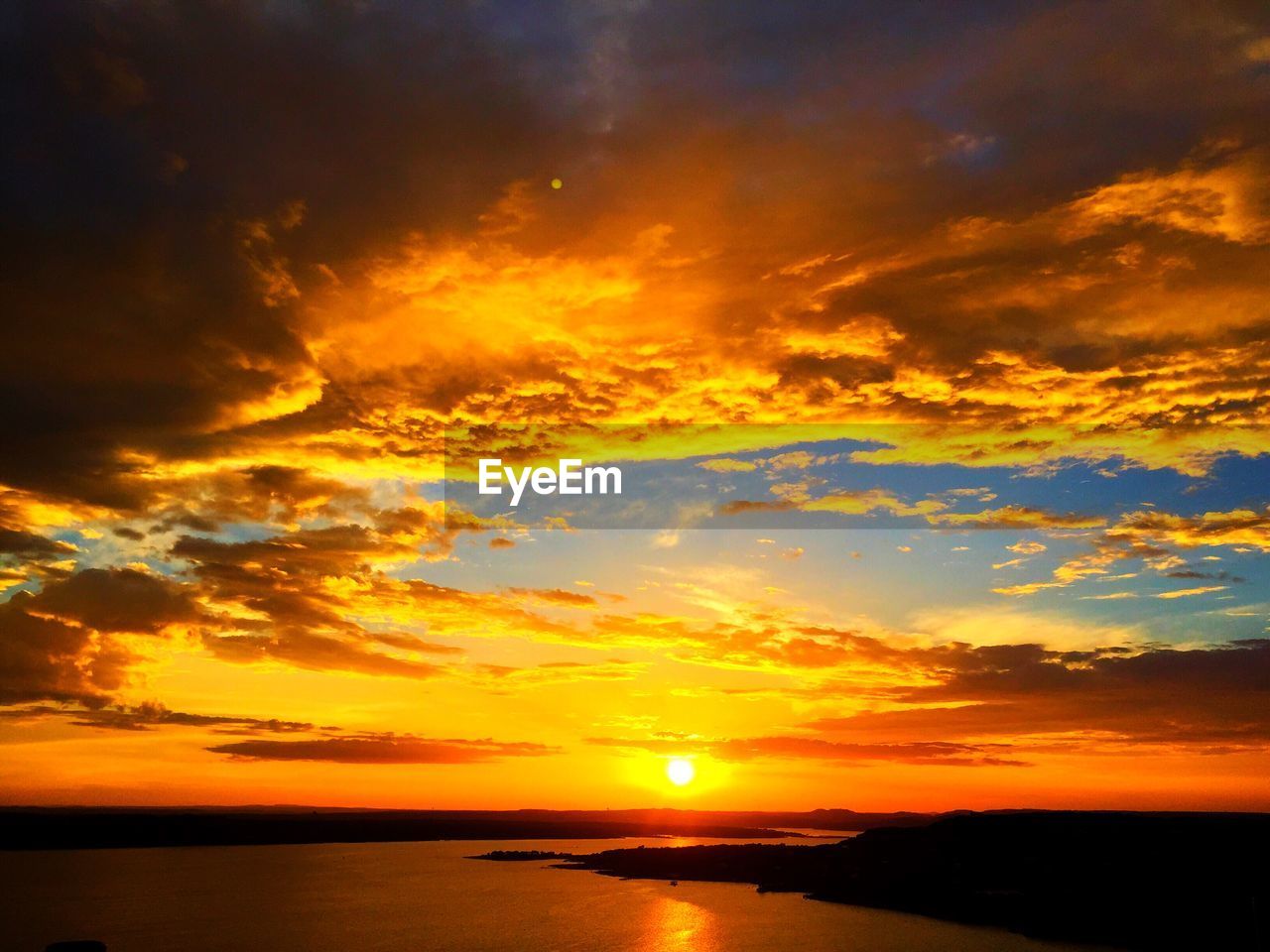 Scenic view of sea against cloudy orange sky during sunset