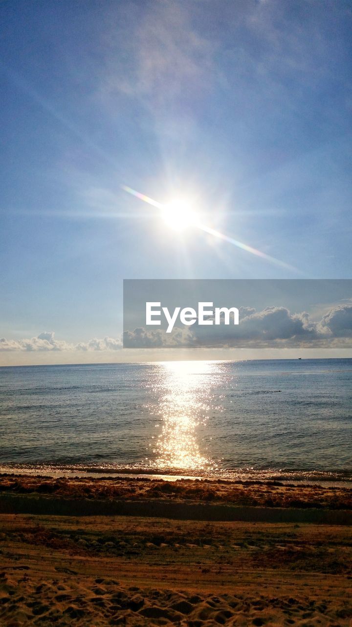 Scenic view of sea against bright sun