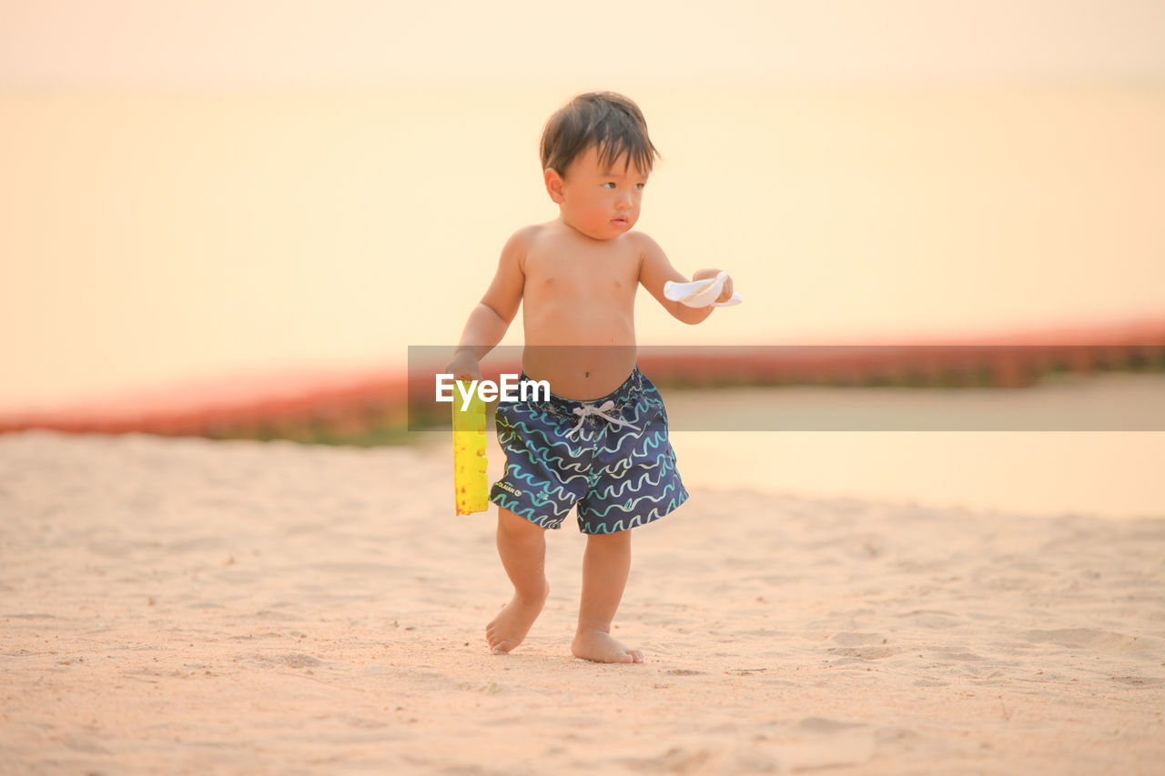 Full length of shirtless boy on beach