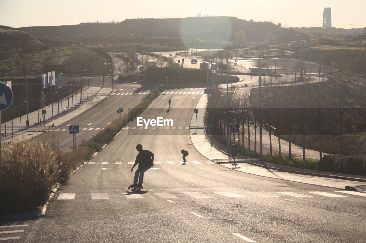 Rear view of people skateboarding on road