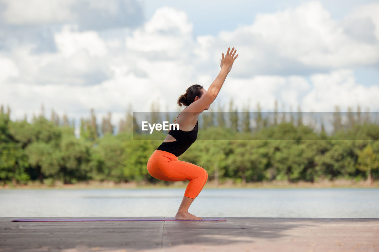 Woman exercising on pier by lake