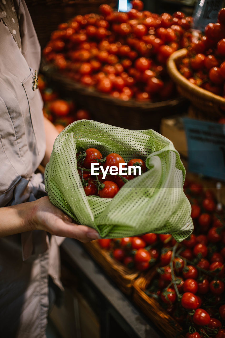 Midsection of woman holding tomatoes in bag at store