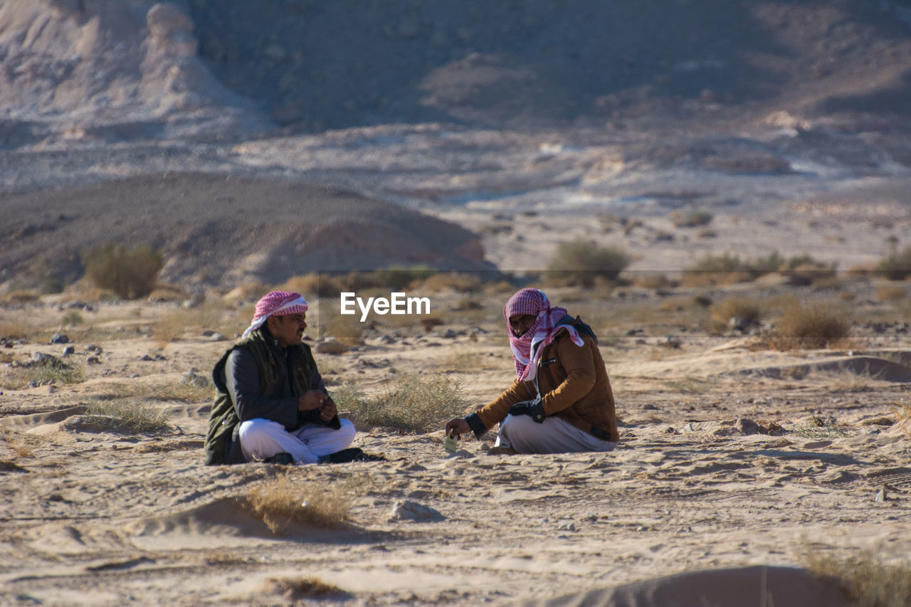 WOMEN SITTING ON SAND