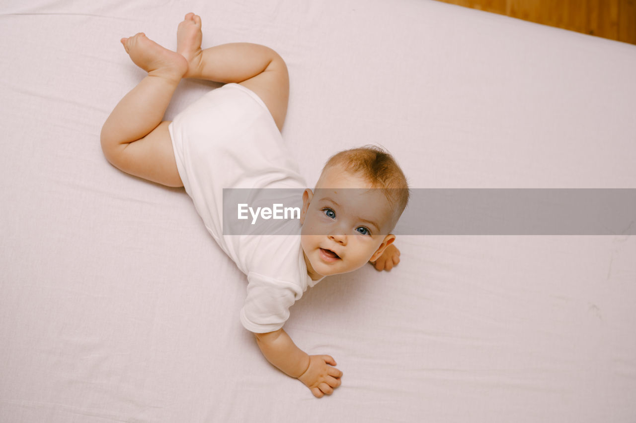 High angle portrait of cute baby lying on bed