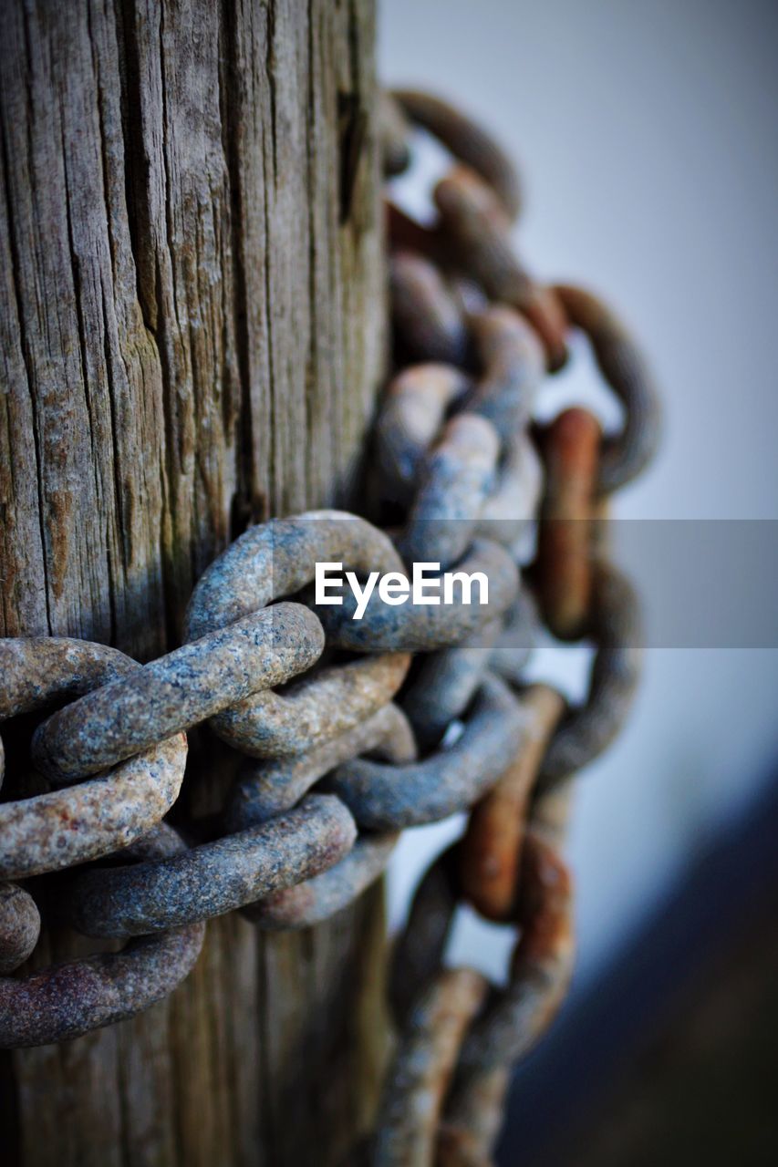 Close-up of rusty chain on wooden post