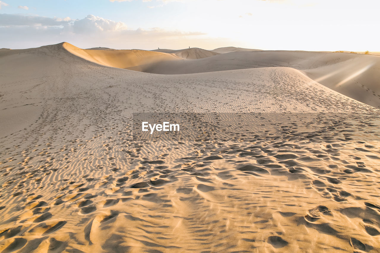 Sand dune with human footprints in desert against sly