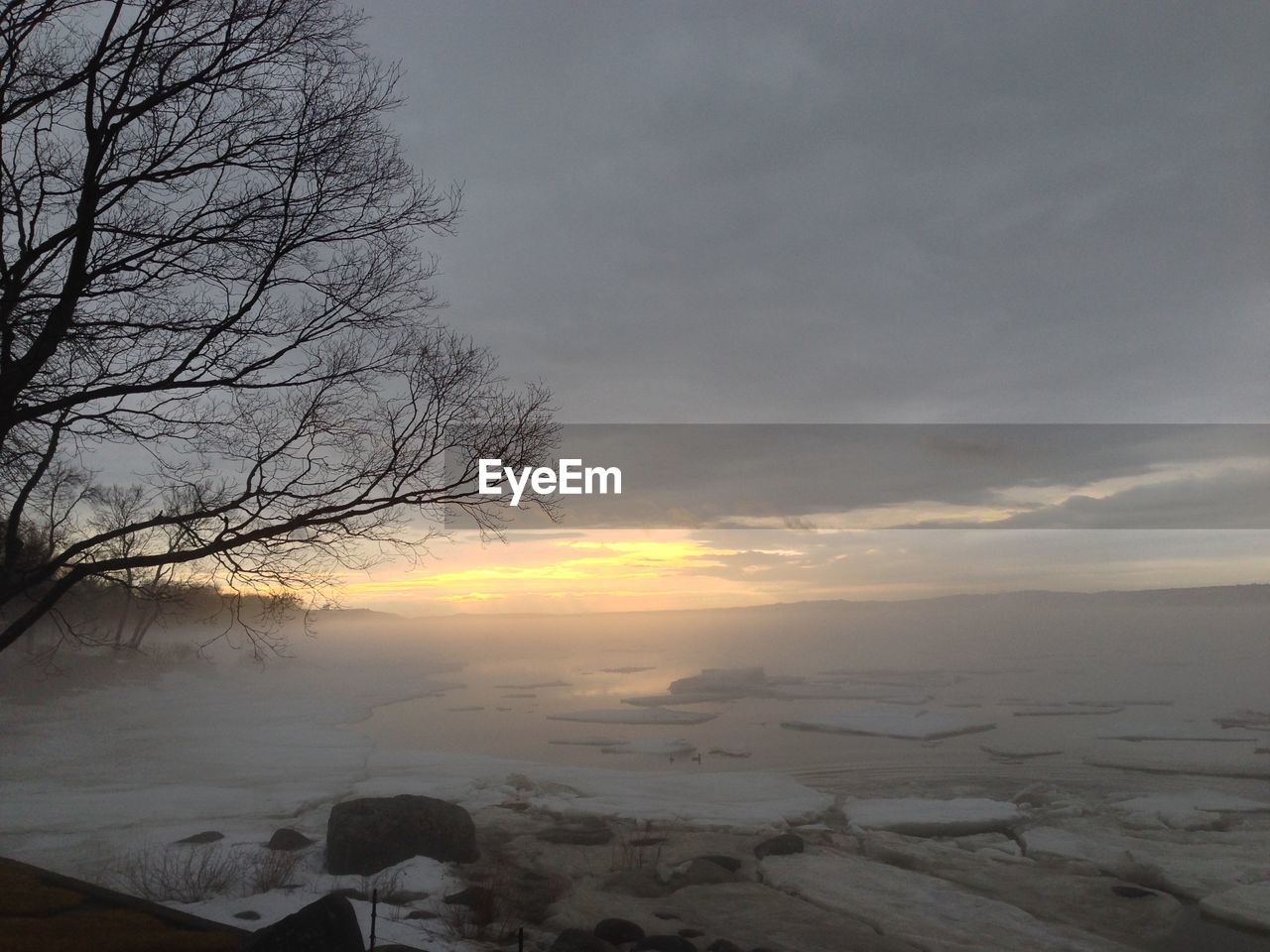 Scenic view frozen lake against cloudy sky during sunset