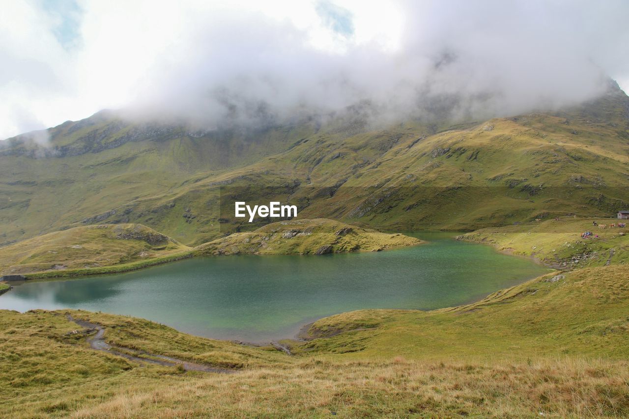 Scenic view of lake and mountains against clouds