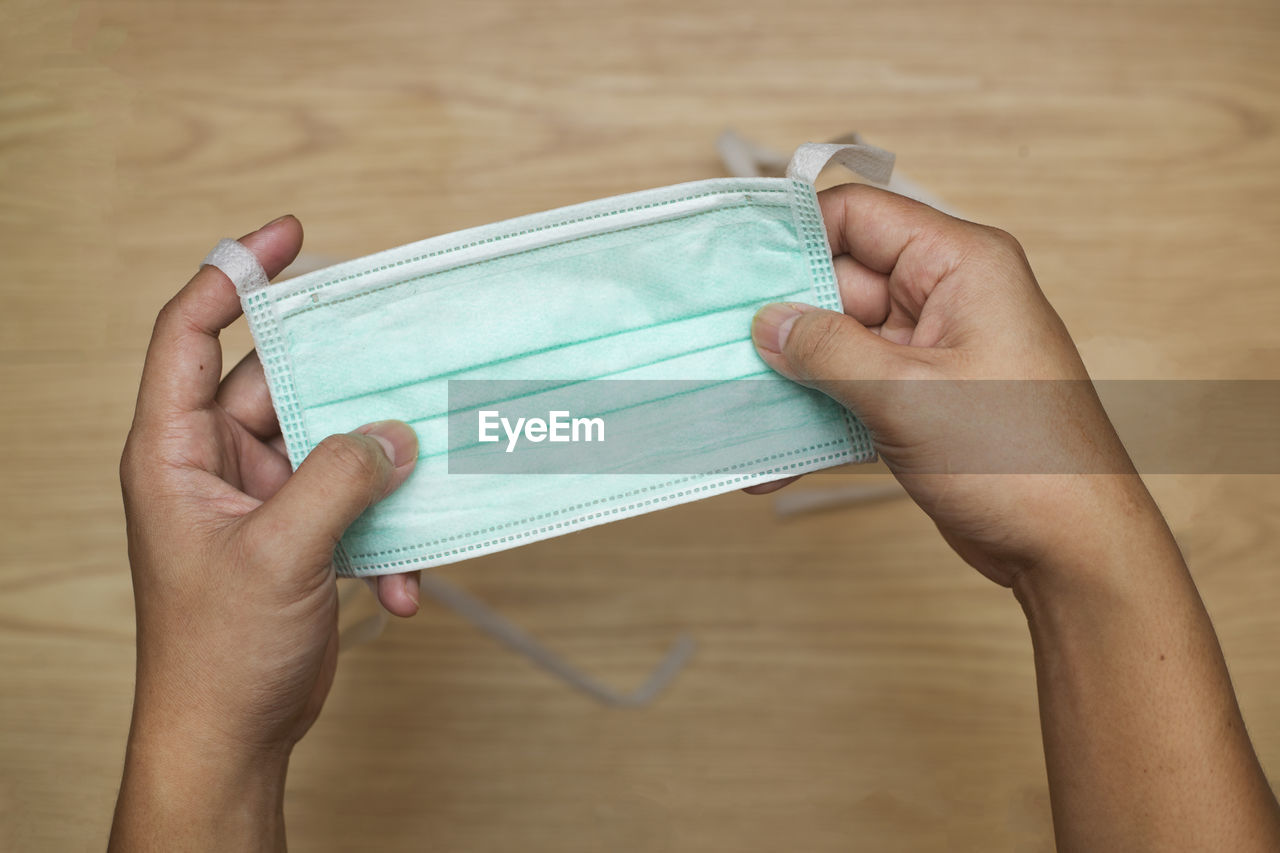 HIGH ANGLE VIEW OF WOMAN HAND HOLDING PAPER WITH TEXT ON TABLE