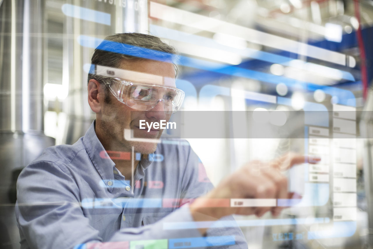 Man wearing safety goggles using transparent touchscreen device