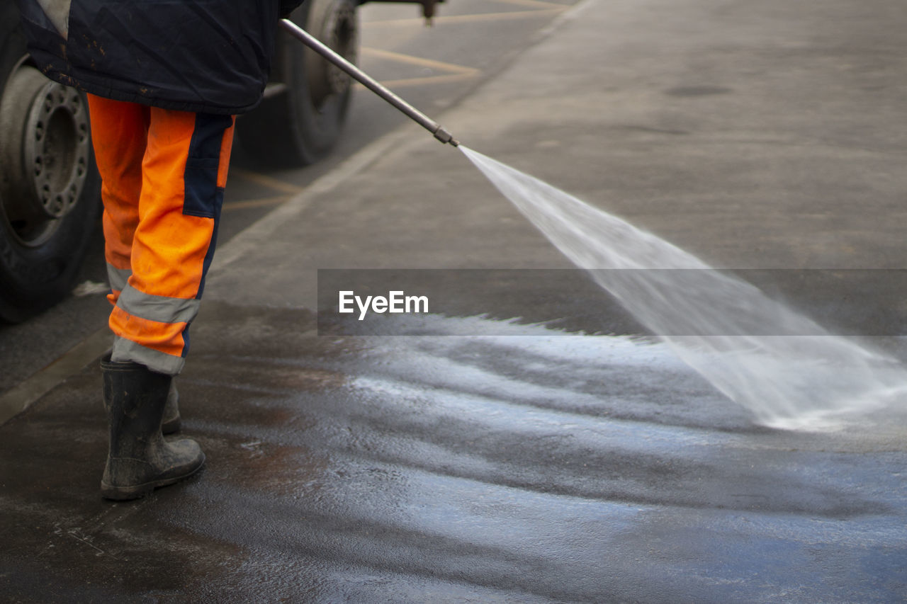 Cleaning up the public place. a jet of water washes the asphalt. disinfection of the bus stop. 