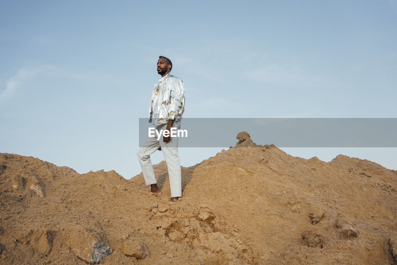 Man wearing silver jacket standing on sand