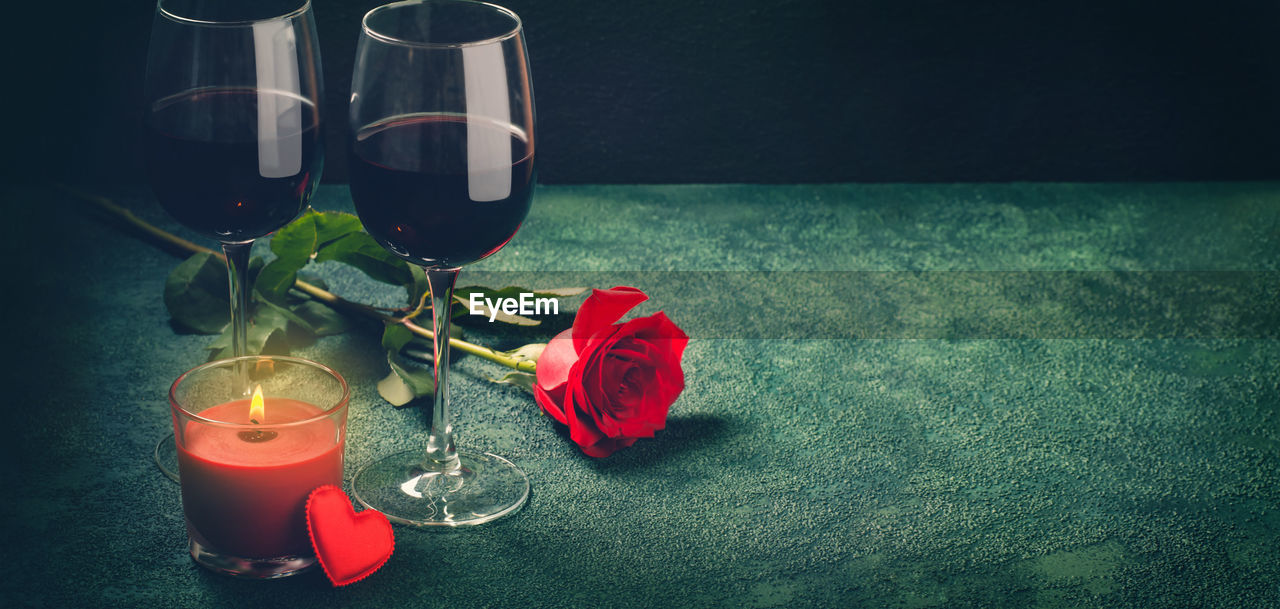 Wine glasses, rose and hearts bokeh lights. valentines day concept. banner format.