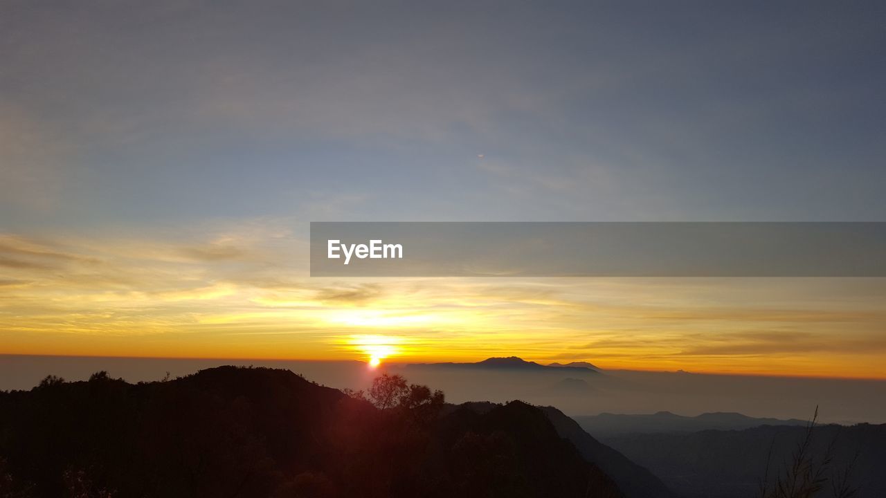 Scenic view of silhouette mountains against orange sky