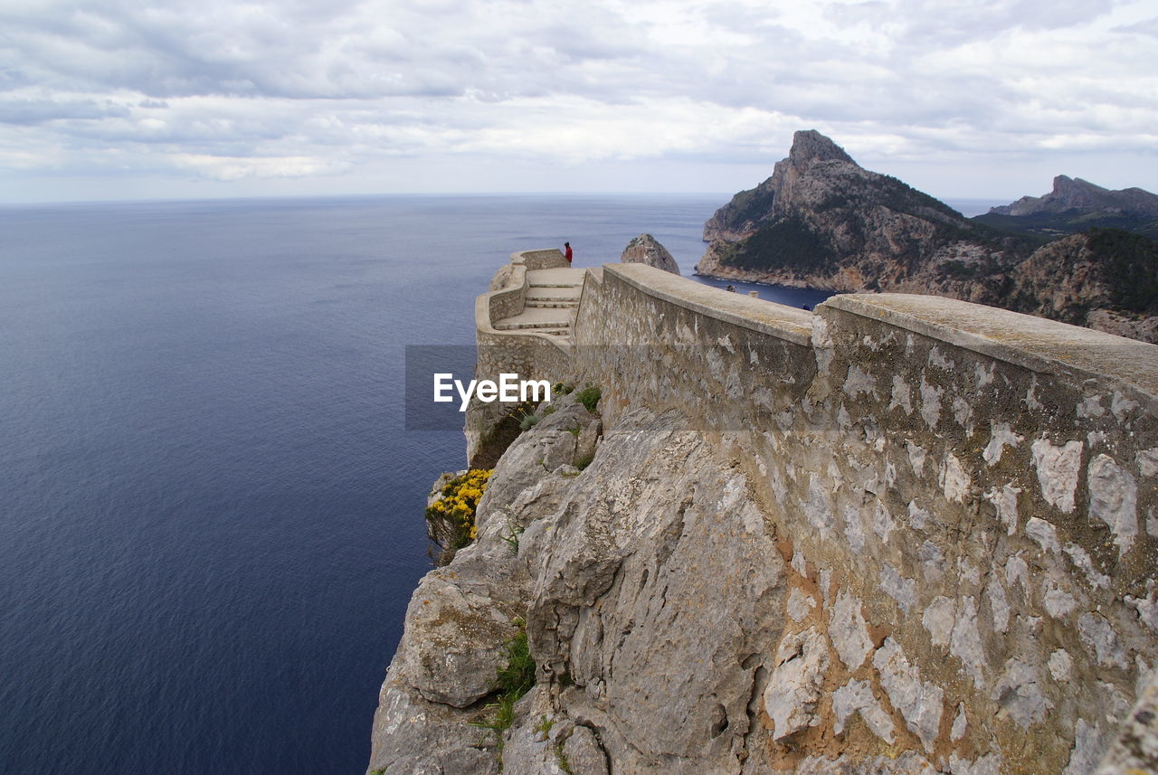 Scenic view of sea by cliff against sky