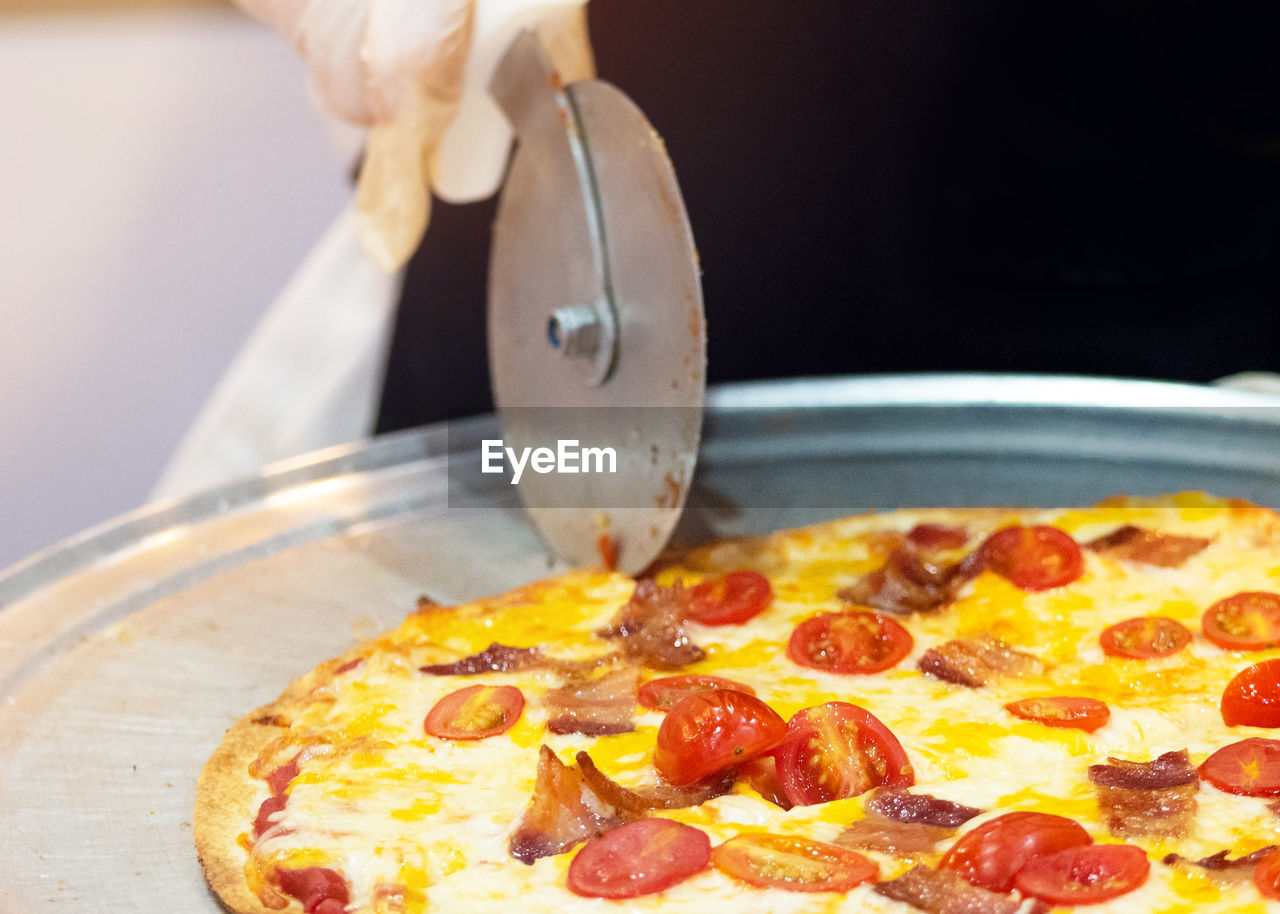 cropped hand of person holding pizza