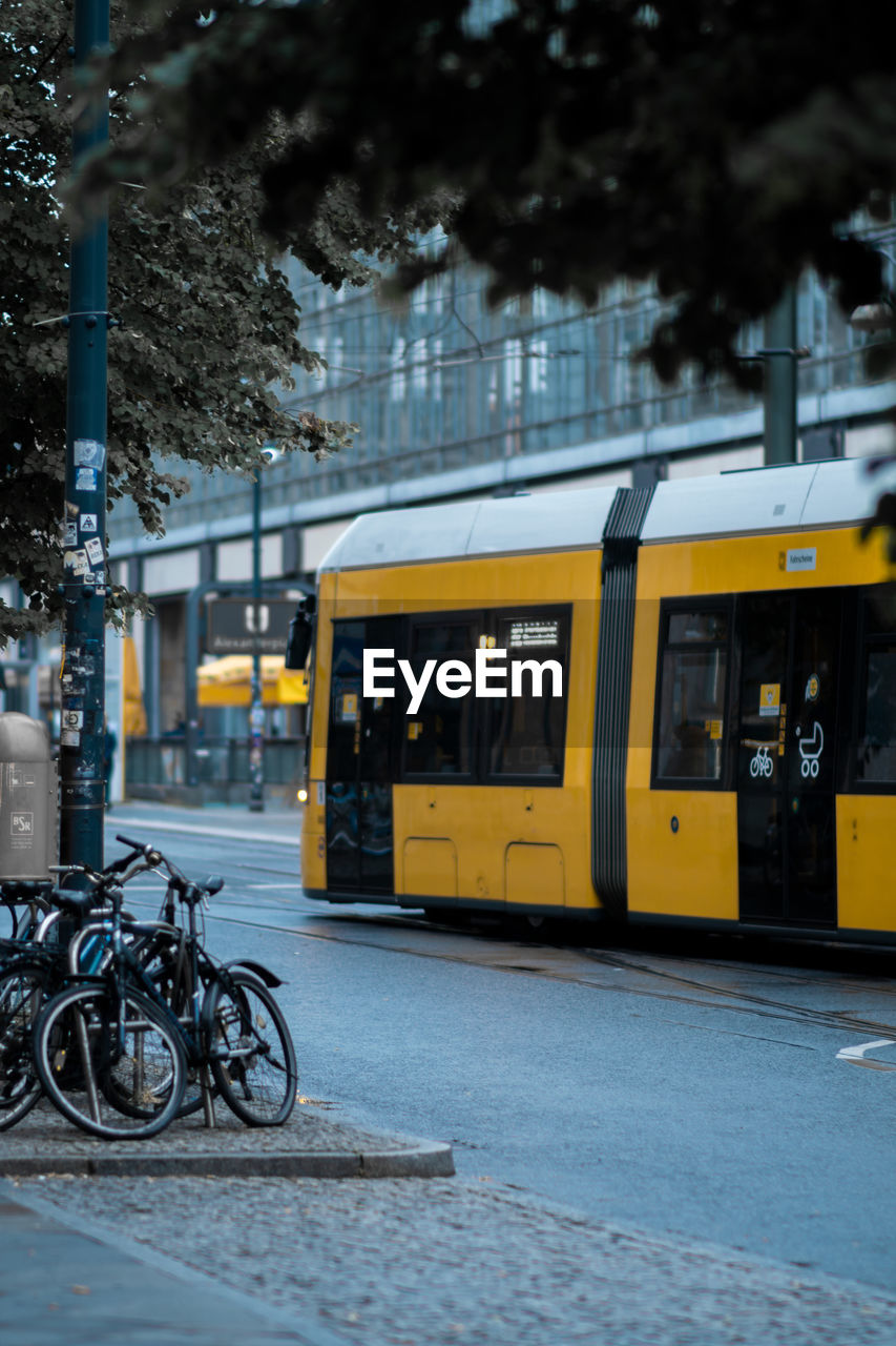 Bicycles parked on street in city with yellow tram passing through
