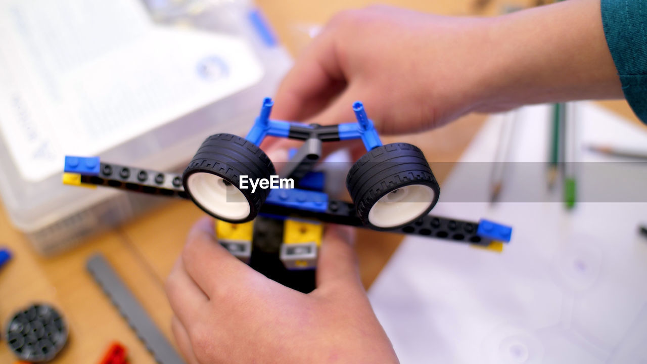 Close-up, children's hands hold a multicolored small robot, machine, assembled from a designer. 