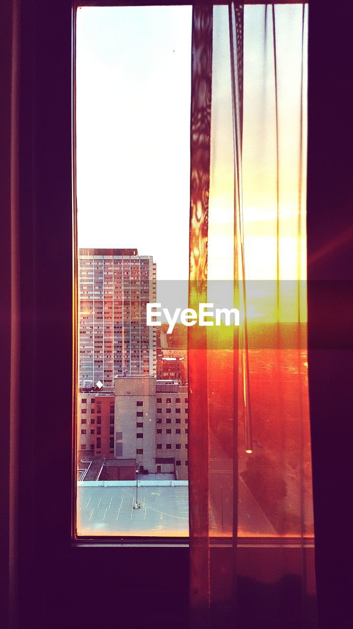 Buildings seen through glass window during sunset