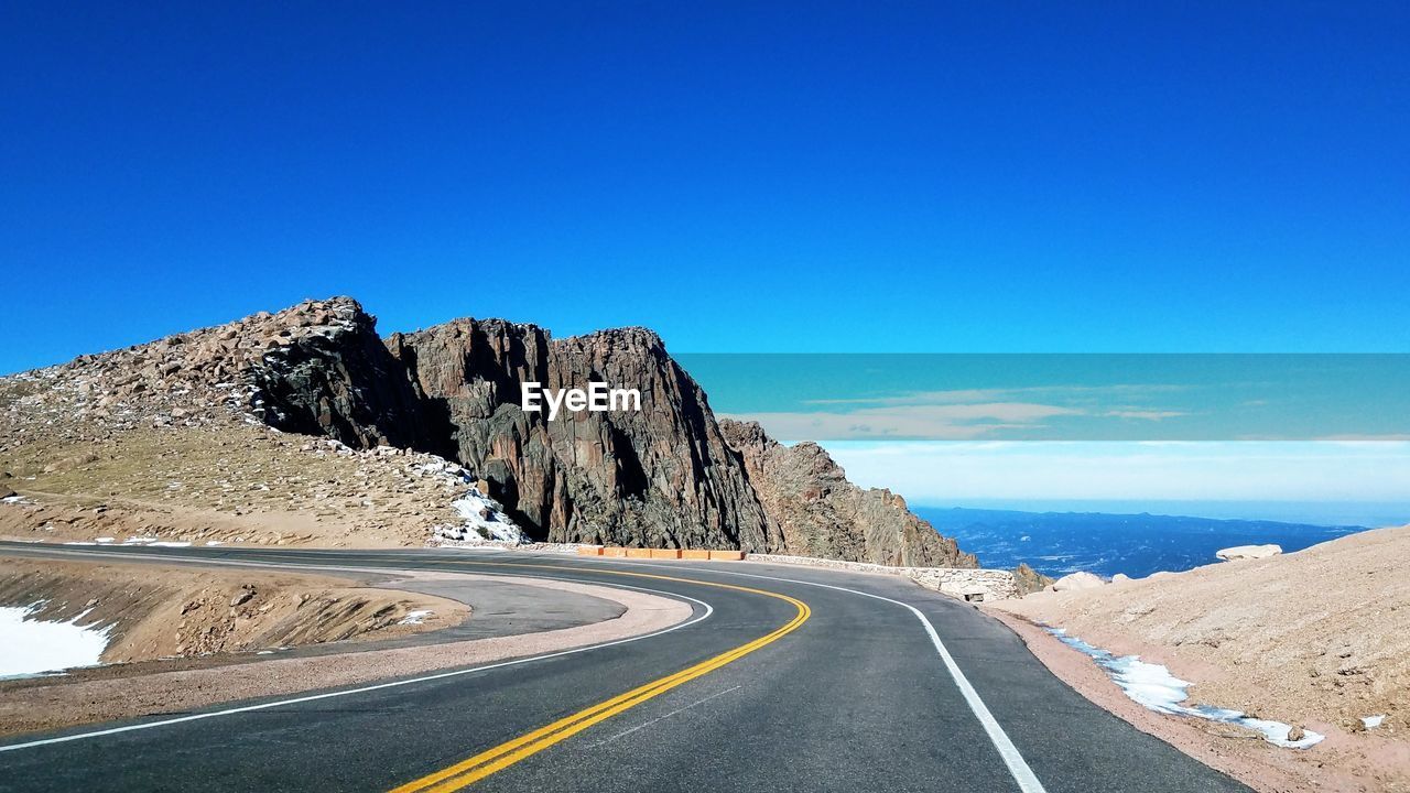 Road by mountain against blue sky