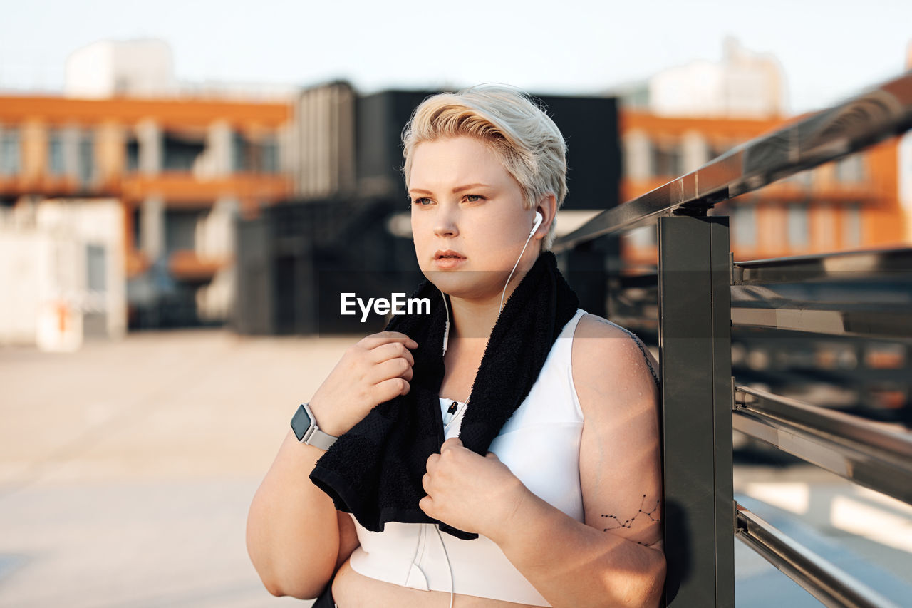 Portrait of young woman standing against railing