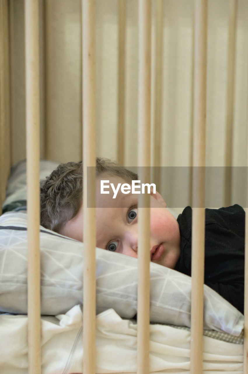 Portrait of boy resting on bed