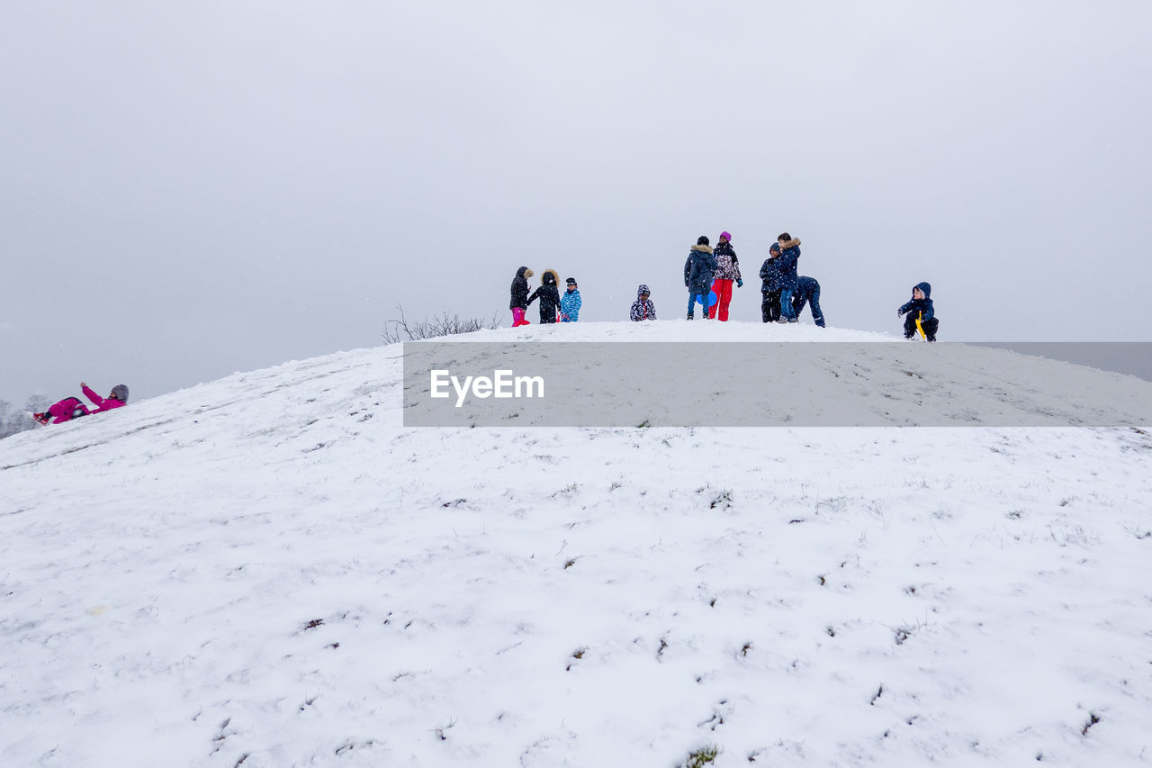 PEOPLE ON SNOWCAPPED MOUNTAINS AGAINST SKY