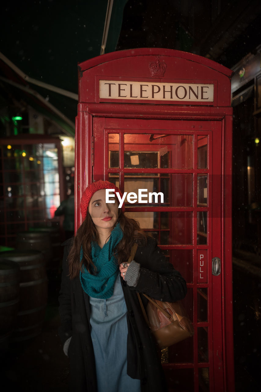 Woman standing against telephone booth