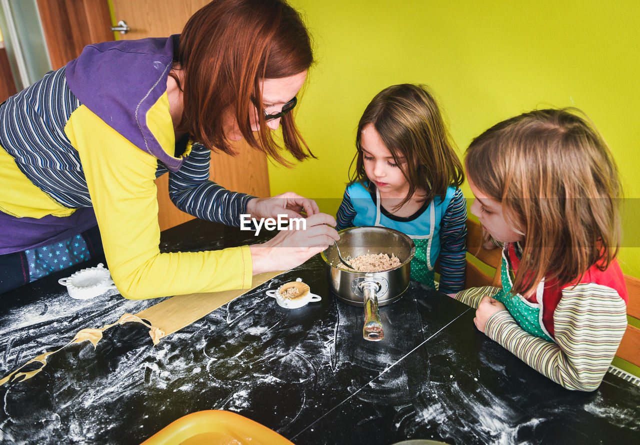 High angle view of mother with daughters preparing food in kitchen