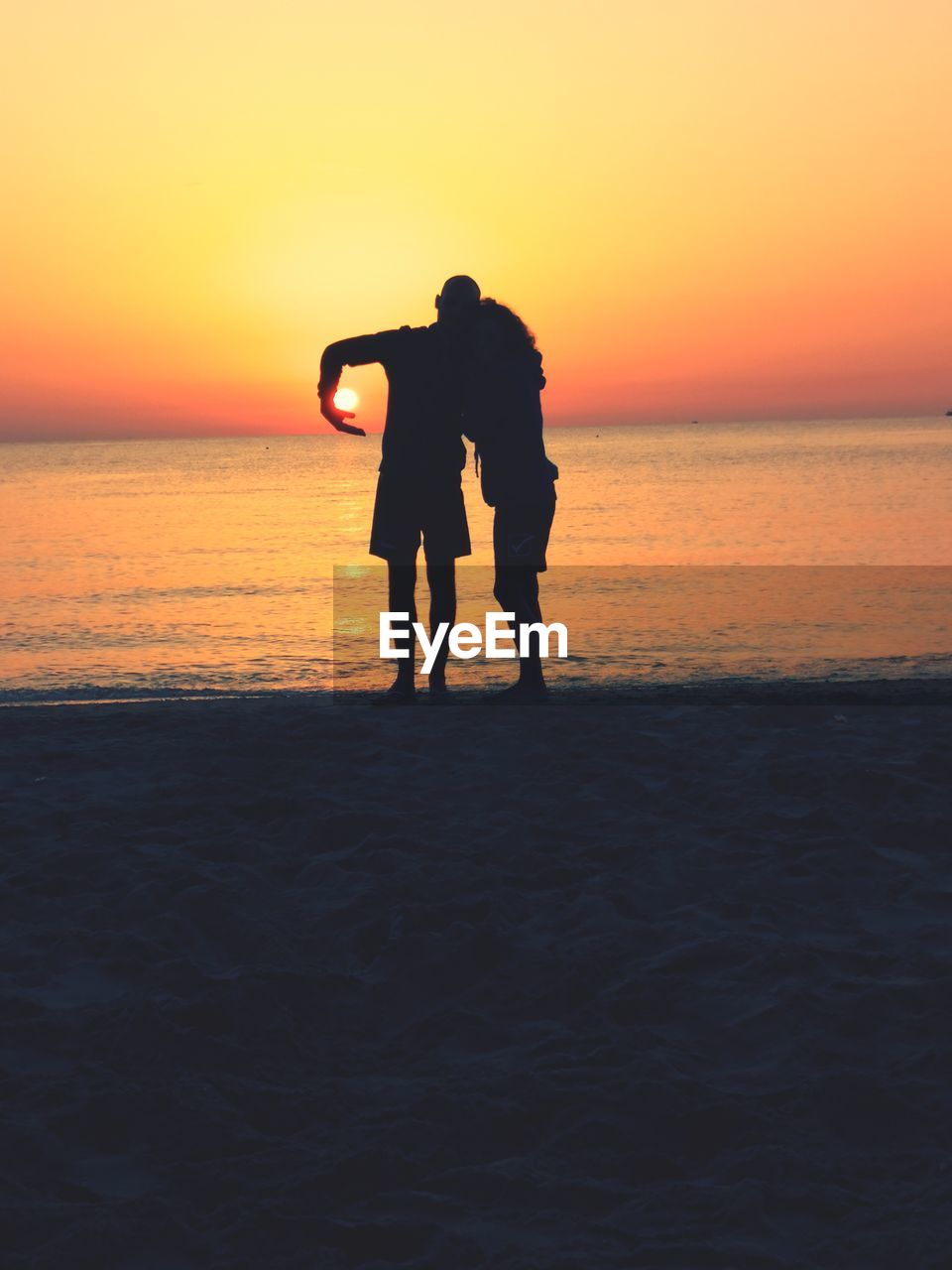 Silhouette boyfriend standing on beach during sunset