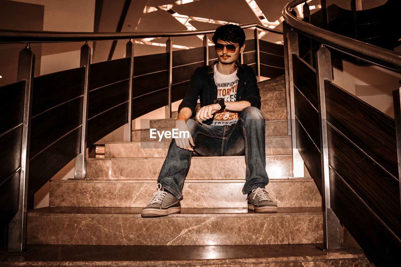 Full length of young man sitting on staircase