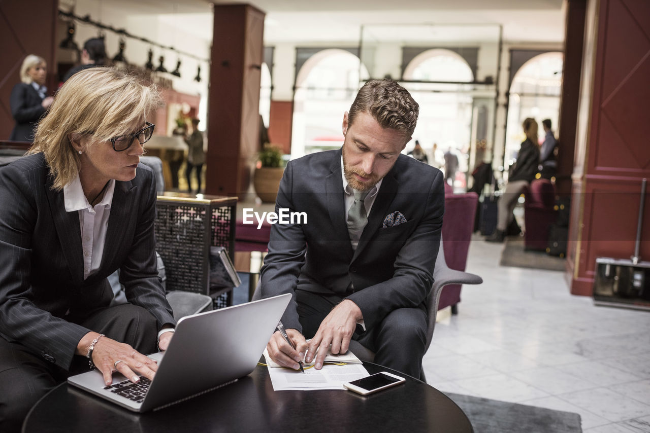 Businesswoman looking at partner signing agreement in hotel reception