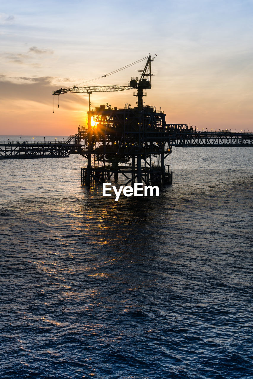 Scenic view of oil field against sky during sunset