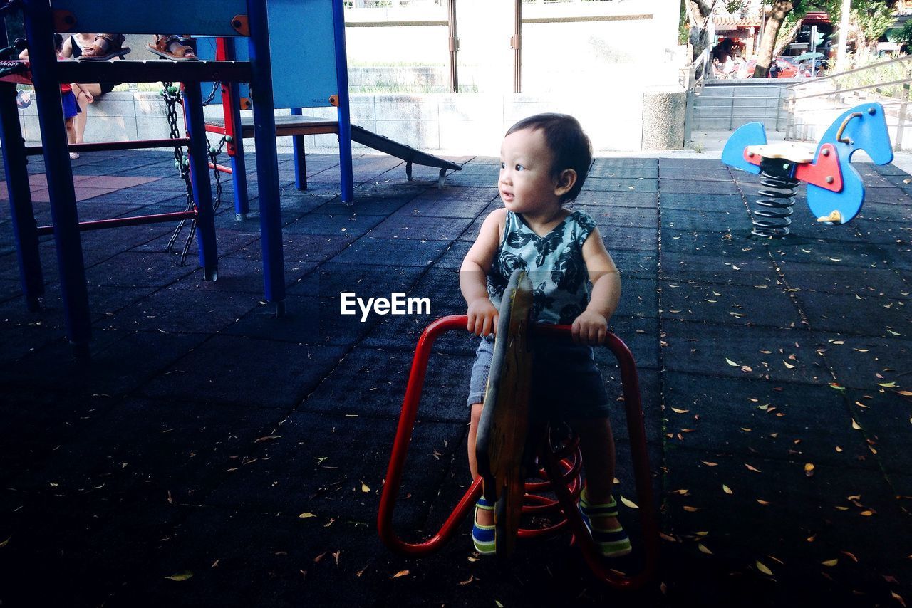 Cute girl sitting on outdoor play equipment at playground