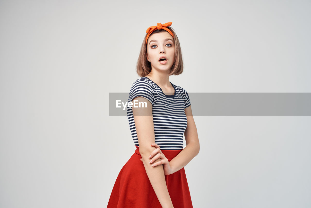 PORTRAIT OF YOUNG WOMAN AGAINST WHITE BACKGROUND