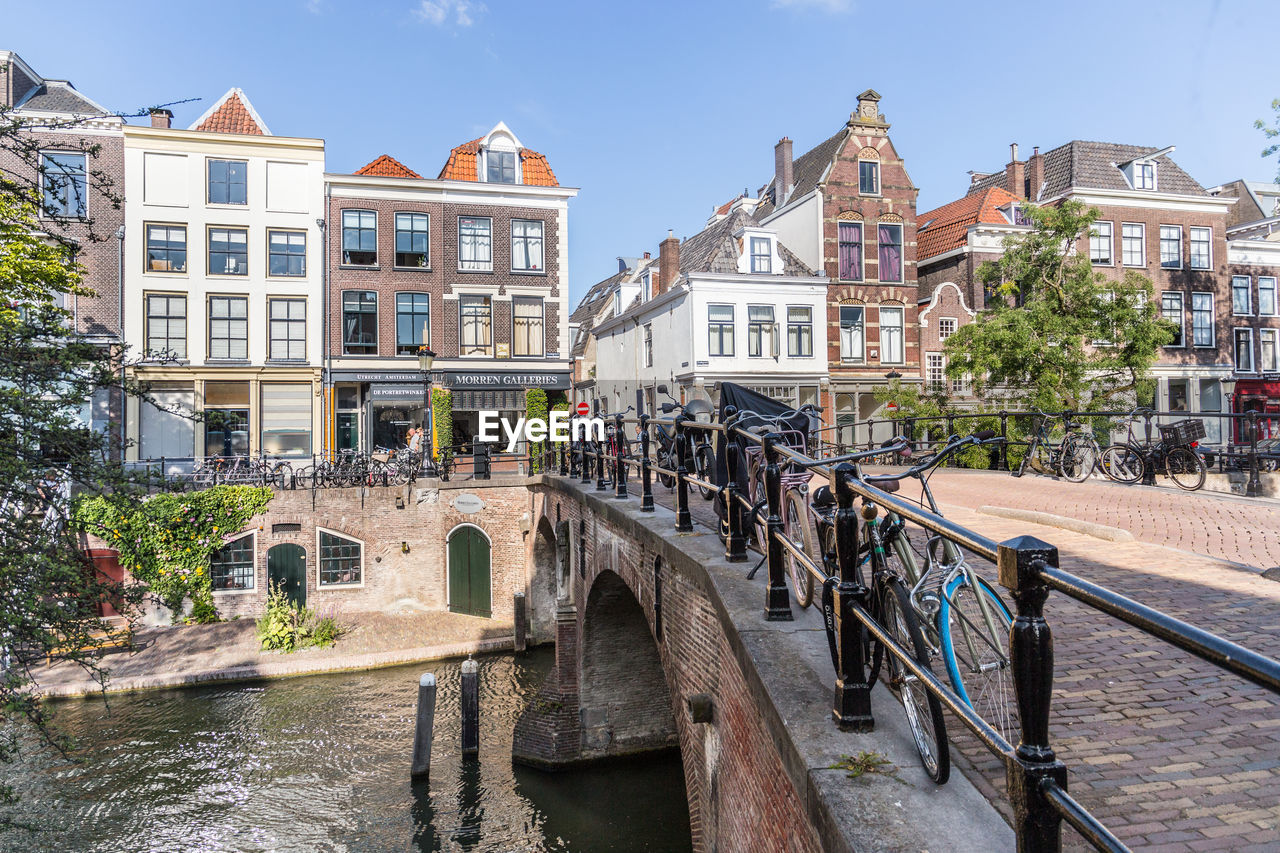 Bridge over canal amidst buildings in city against sky