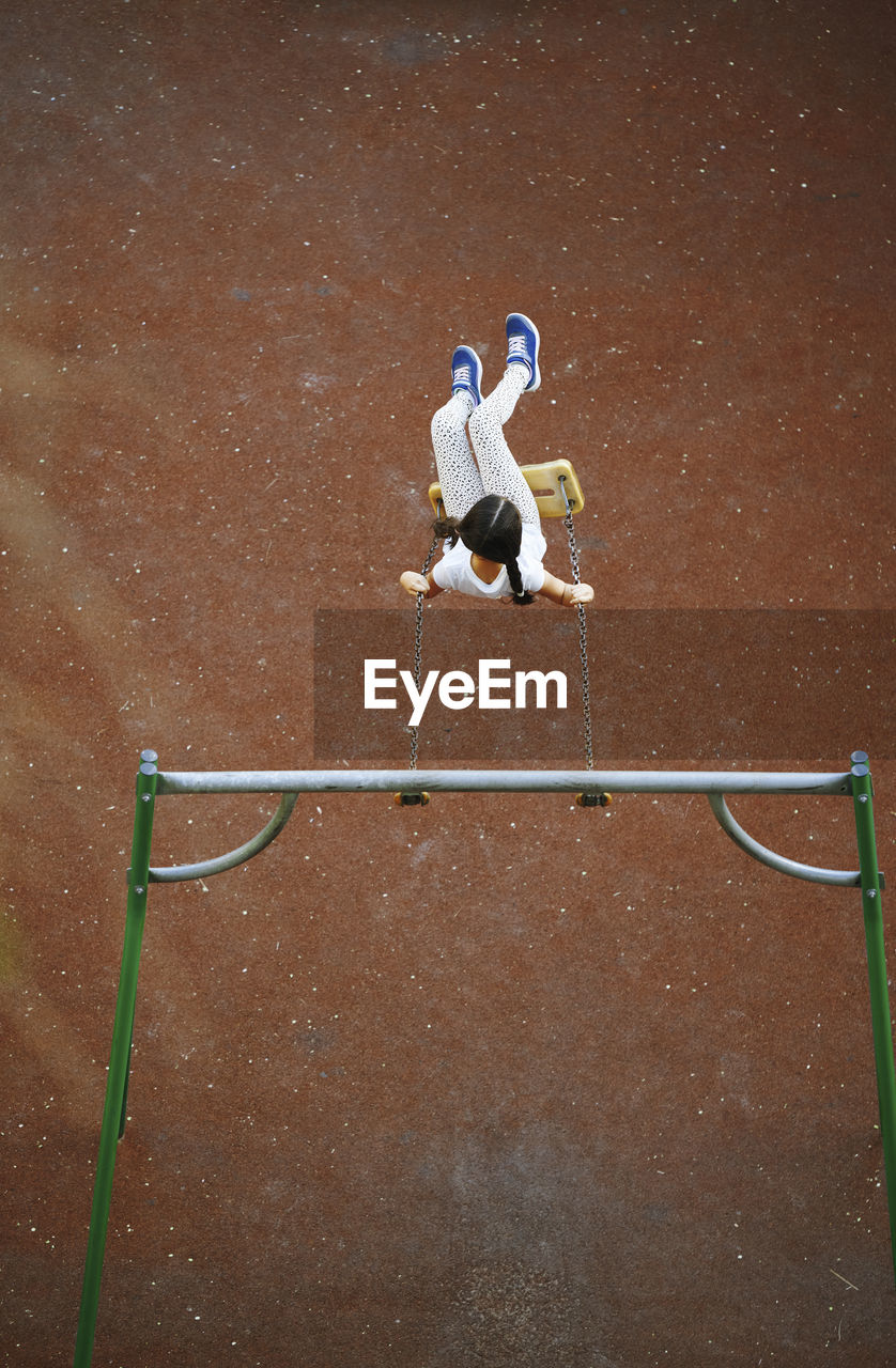 Playful girl enjoying on swing at playground