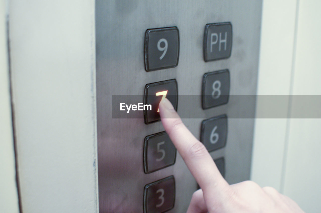 Close-up of hand pressing button in elevator