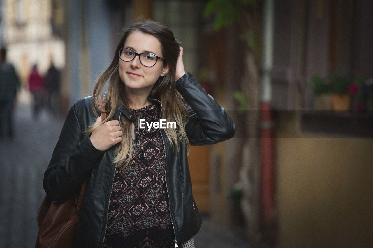 Portrait of woman smiling while standing in city