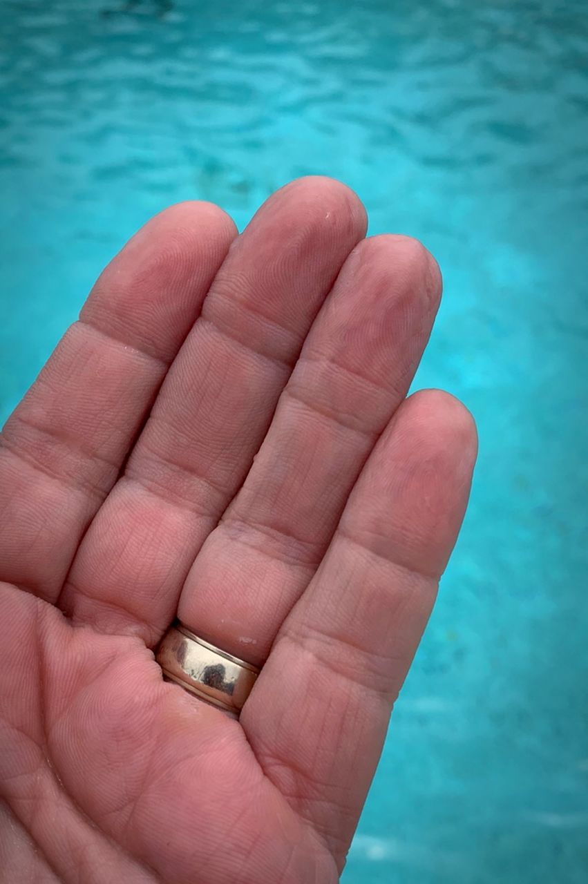 CLOSE-UP OF PERSON HOLDING HAND SWIMMING POOL